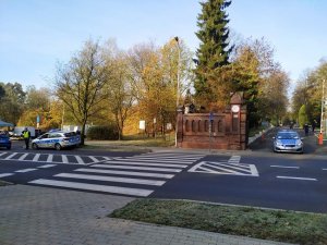 dwa samochody oznakowane policyjne w pobliżu cmentarza