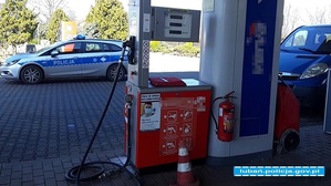 dystrybutor LPG za nim zaparkowany pojazd służbowy policji