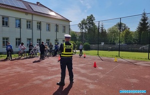 policjant podczas rozmowy z uczniami szkoły na temat egzaminu na  kartę rowerową