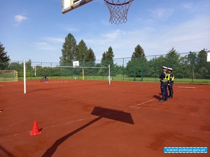 policjanci stoją na płycie boiska w oddali widać osobę na rowerze