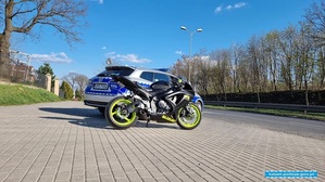oznakowany pojazd policyjny i zaparkowany obok motocykl