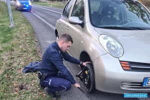 policjant podczas naprawy koła