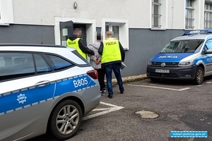 osoba zatrzymana doprowadzana na przesłuchanie przez policjantów