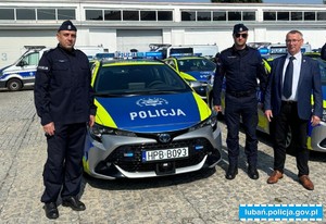 Podkomisarz Dariusz Ślęzak, Pan Zbigniew Zjawin i umundurowany policjant stoją obok pojazdu oznakowanego