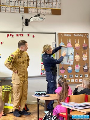 policjantka wraz ze strażakiem omawia zasady bezpieczeństwa podczas pobytu na feriach