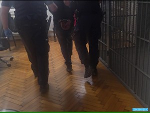 umundurowani policjanci doprowadzają osobę zatrzymaną