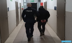 policjant prowadzi osobę zatrzymaną do PDoZ