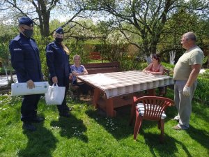 Policjanci stoją obok działkowców i rozmawiają z nimi