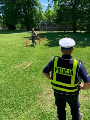 Policjant wskazuje uczniom jak maja prawidłowo jechać rowerem